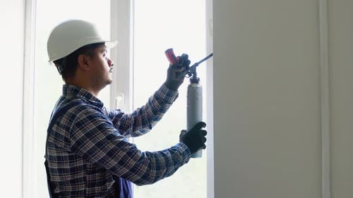 Indian Worker is Applying Polyurethane Foam to Fill Gap Between Sash and Window Frame