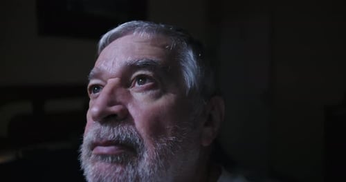 Close up of elderly man gazing upward indoors reflecting in peaceful solitude