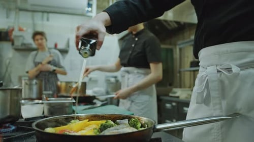 Chefs Preparing Fish and Vegetables in Kitchen