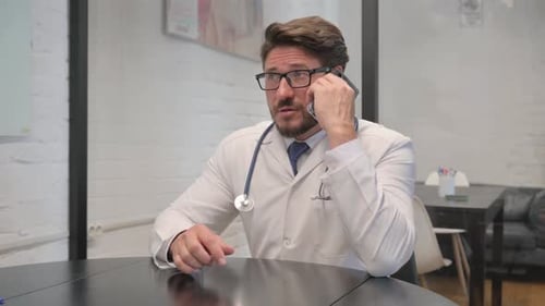 Middle Aged Doctor Talking on Phone in Clinic