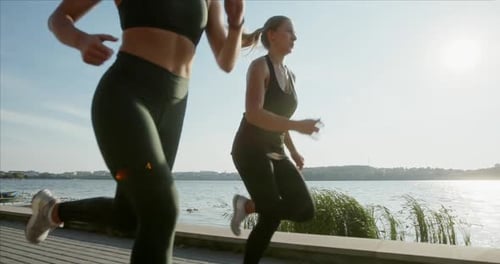 Athletische Frauen laufen im Morgensonnenlicht am Meer