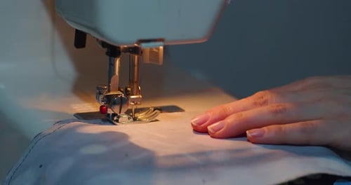 Woman Using Sewing Machine to Stitch White Fabric