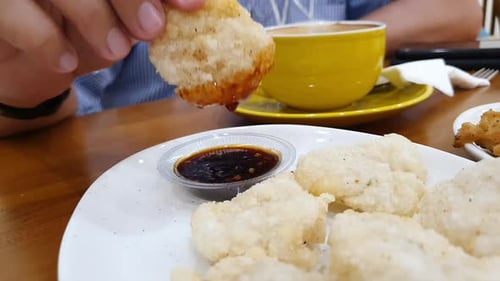 a man dipping cireng in the sauce. Cireng is a traditional Indonesian food made from tapioca flour