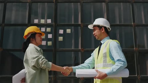 Architect and engineer work together on floor plan drawings outside construction site building