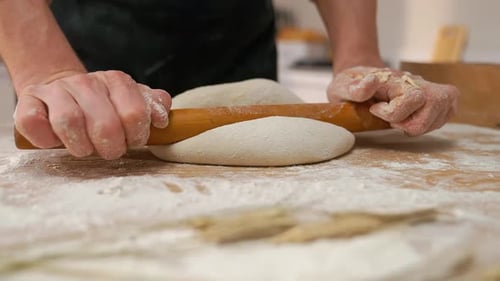 Hands Rolling Dough with Wooden Rolling Pin