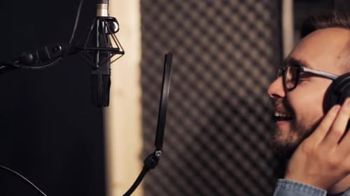 Male singer with headphones performing a song in a sound recording studio