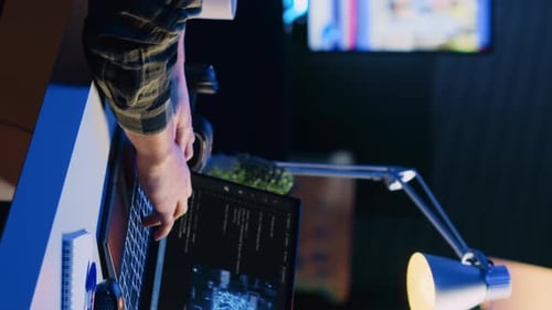 Person Typing on Laptop in Dimly Lit Room