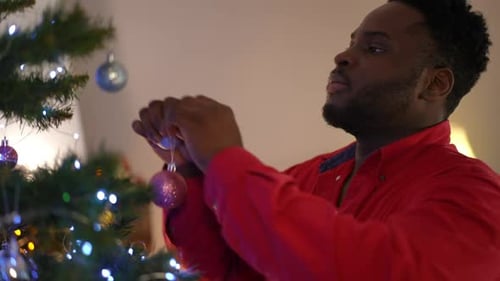 Man Decorating Christmas Tree with Ornaments