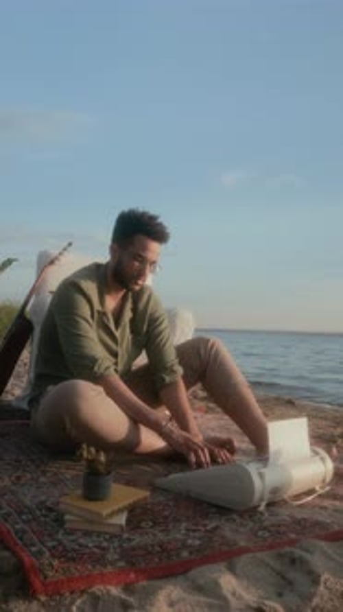 Vertical of Black Male Novelist Working on New Book on Typewriter on Beach