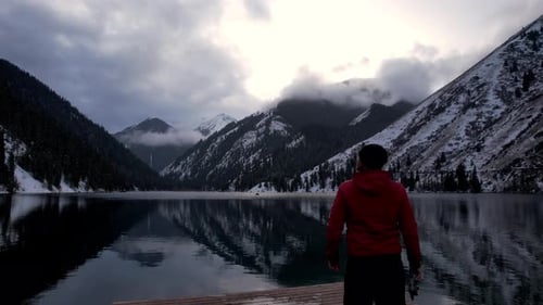 The Guy Standing on the Pier Admires Mountain Lake