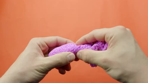Hands stretch and squeeze bright pink floam slime in satisfying close-up view