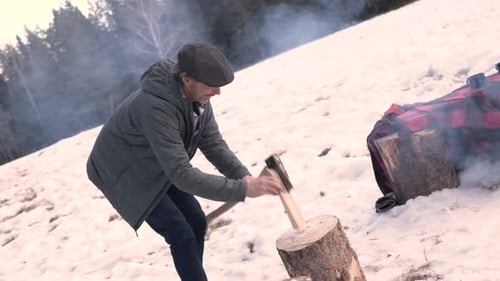 Man Chopping Wood in Snowy Outdoor Winter Setting