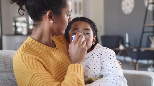 Woman Helps Child Use Inhaler on Couch