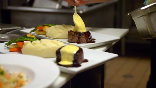 Chef plating food with sauce in restaurant kitchen