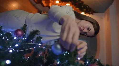 Woman Decorating Christmas Tree in Home at Night
