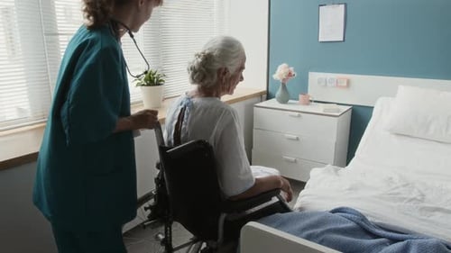 Physician Pushing Wheelchair of Elderly Patient, Stopping in Her Hospital Room