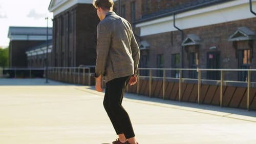 Young Man Skateboarding Along Urban Building on Sunny Day