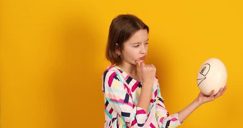 Child Holding a Decorated Egg with a Drawn Face