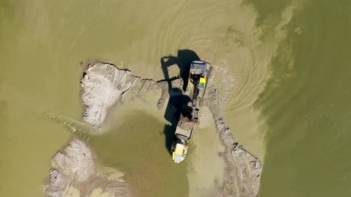 Luftaufnahme von Baggerladern, die mit Schaufeln mit einer Drohne Sand und Kies aus dem Fluss graben