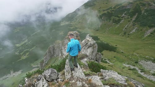 A man in blue clothes, on the top of a mountain
