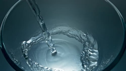 Water being poured into a clear glass bowl