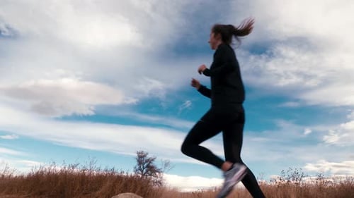 Woman Runs Through Grassy Rural Landscape