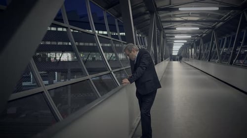 Man in Suit Looking over Walkway at Night