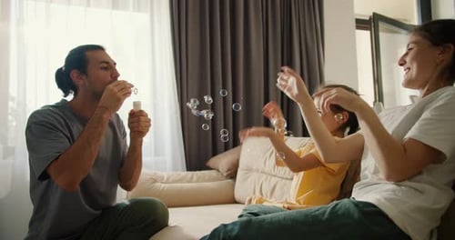 Family Fun Blowing Bubbles on Couch