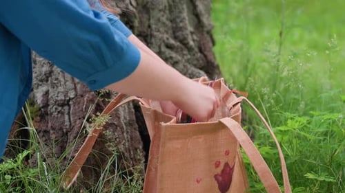 Primer plano de una persona que devuelve hilos de bordar a una bolsa al aire libre