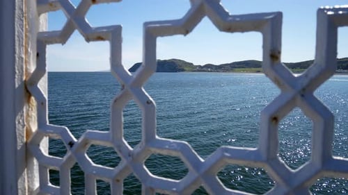 North Wales green mountain island coastline through ornate patterned wrought iron railing jib up lef