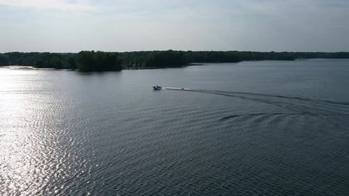 Outdoor aerial shot of man wakeboarding on lake in day time. Water skiing on lake behind a boat.