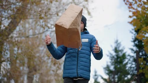 Boy Walking and Pouring Dry Leaves From Bag in Autumn Forest