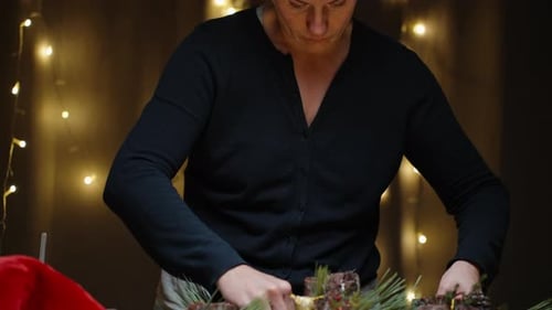 Woman Crafts Christmas Centerpiece Under Warm Lighting
