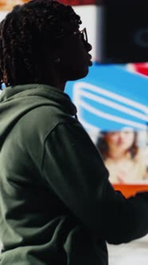 Una persona de vídeo vertical ve clips en un videowall disfrutando de la tecnología que une a personas de todo el mundo