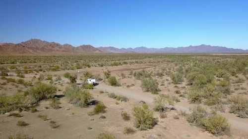 Aerial, drone shot following a work truck, driving slowly on a dirt road on a open desert, sunny day
