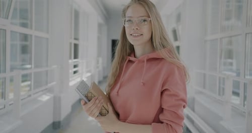 Slow Motion Portrait of Beautiful Young Woman Student Standing in University Hall Holding Books
