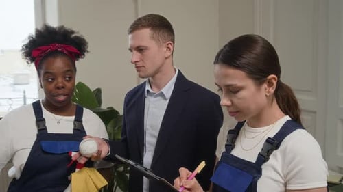 Employé de bureau discutant du nettoyage d'une table avec deux femmes concierges