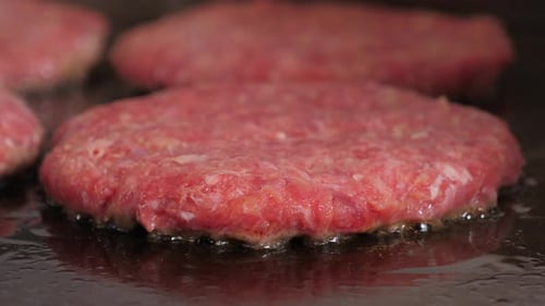 A Closeup of a Juicy Meat Burger Patty is Fried in the Restaurant Kitchen
