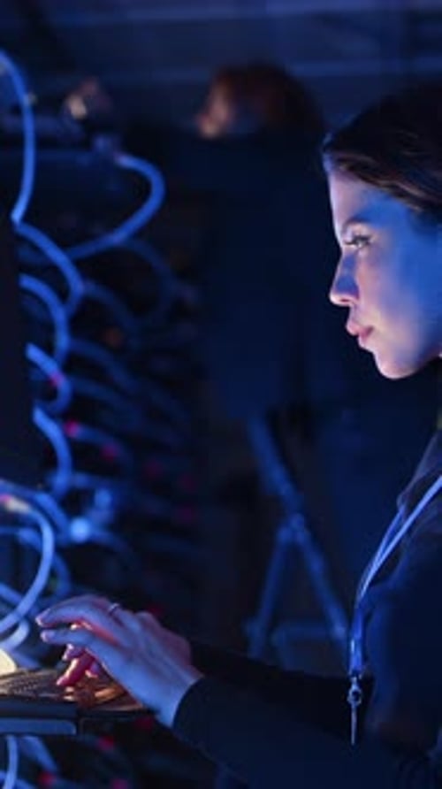 Woman Typing in Dark Futuristic Server Room