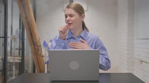 Young Woman Coughing at Desk in Office
