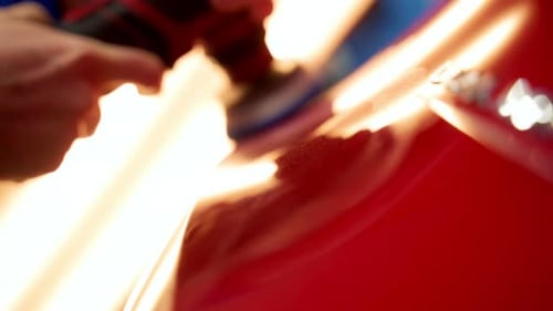 Man Worker Polishing the Red Car Body in a Auto Body Shop