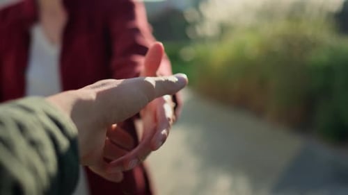 Handshake of a man and a woman on the street on a bright sunny day. The girl shakes hands a symbol