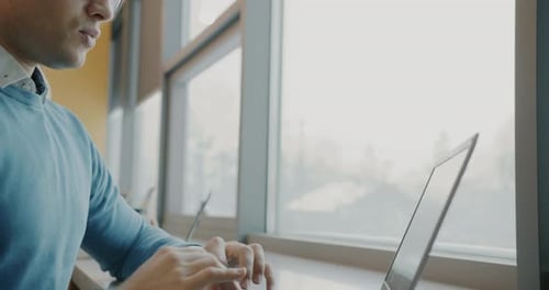 Tiltup of Ambitious Businessman Typing with Modern Laptop in Shared Office Room