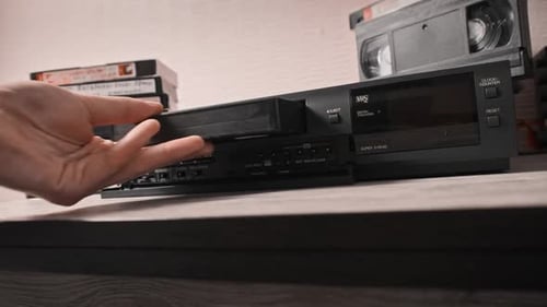 Hand Inserts VHS Tape into VCR Machine