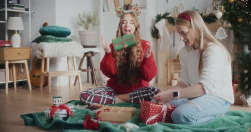 Young Women Wrapping Christmas Gifts Together Indoors