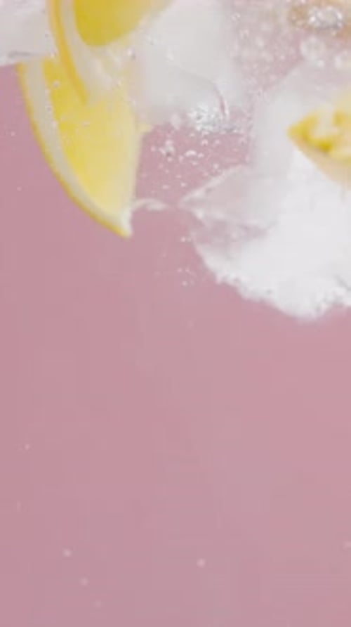 Lemon and Ice Falling in Pink Liquid