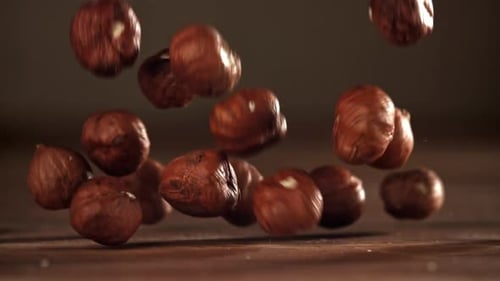 Hazelnuts Falling in Slow Motion onto Wood Table