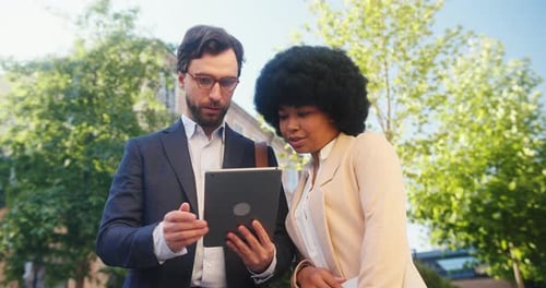 Business Partners Discuss Necessary Details on Tablet in Park