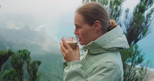 Closeup Young Happy Carefree Woman Holding Coffee in Glass Cup in Hands and Drinking with Mountain