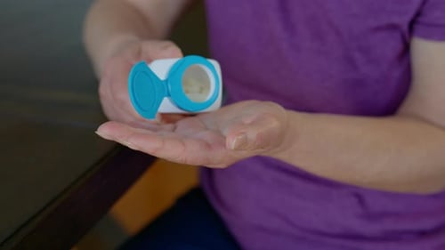 Close Up Footage of Elderly Hands Pouring Pills From an White Prescription Bottle Into the Palm with